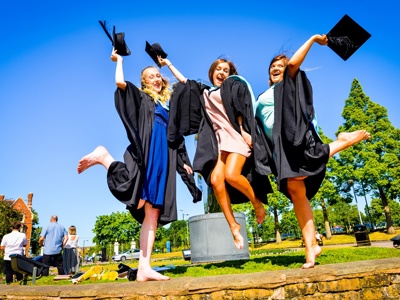 three graduates jumping in the air