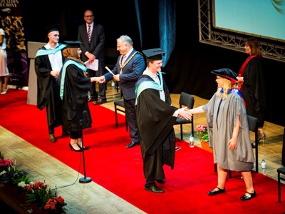graduates on stage getting scrolls